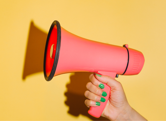 woman's hand holding a red megaphone against a yellow background